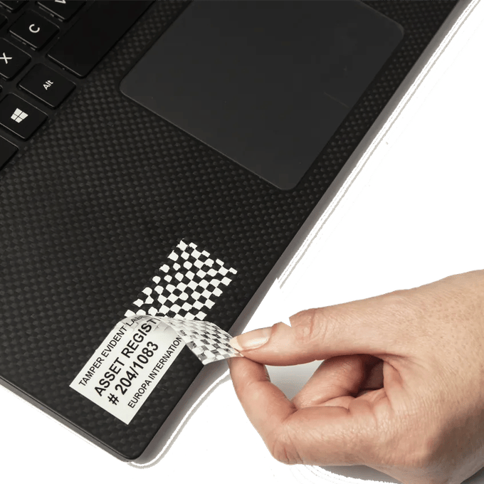 Mano colocando etiqueta Brother de seguridad con evidencia de manipulación en laptop