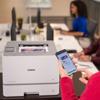 Person using smartphone to print from Brother HL-L8570CDW wireless color laser printer in office