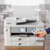 Brother MFC-J6975DW all-in-one printer with hand holding ID badge near wireless NFC touchpoint
