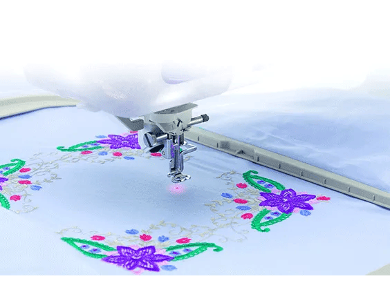 Brother sewing machine embroidering purple flowers with green leaves on white fabric