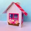 Decorative paper house craft with red roof, window box, and colorful flowers on pastel background