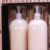 Etiqueta Brother TZe-221 en botella de champú en organizador de baño con fondo de madera