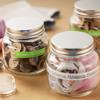 Glass jars with gold lids holding brown and pink buttons on wooden craft table