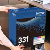 Brother TN331 3-pack toner cartridge box held in office workspace