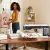 Woman using Brother embroidery machine with touchscreen to create custom jacket design at home