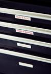 Brother laminated label tape on storage drawers with red text on white background