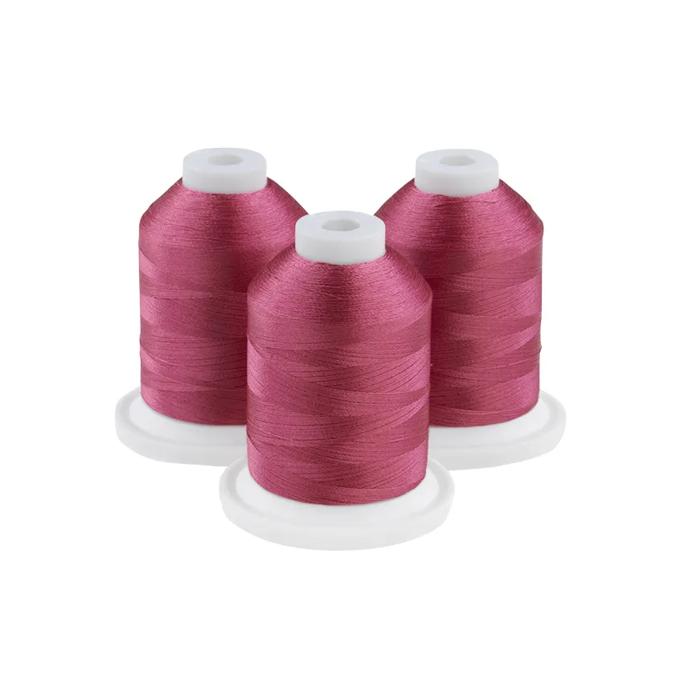 Three pink embroidery thread spools on white bases