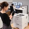 Woman using smartphone to print on Brother HL-L6415DWT wireless laser printer in office