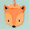 Orange fox-shaped wooden ornament with string on light blue background