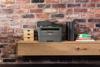 Brother MFC-L2710DW monochrome laser all-in-one printer on wooden shelf in home office