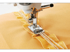 Brother sewing machine presser foot stitching decorative ruffled trim on golden fabric