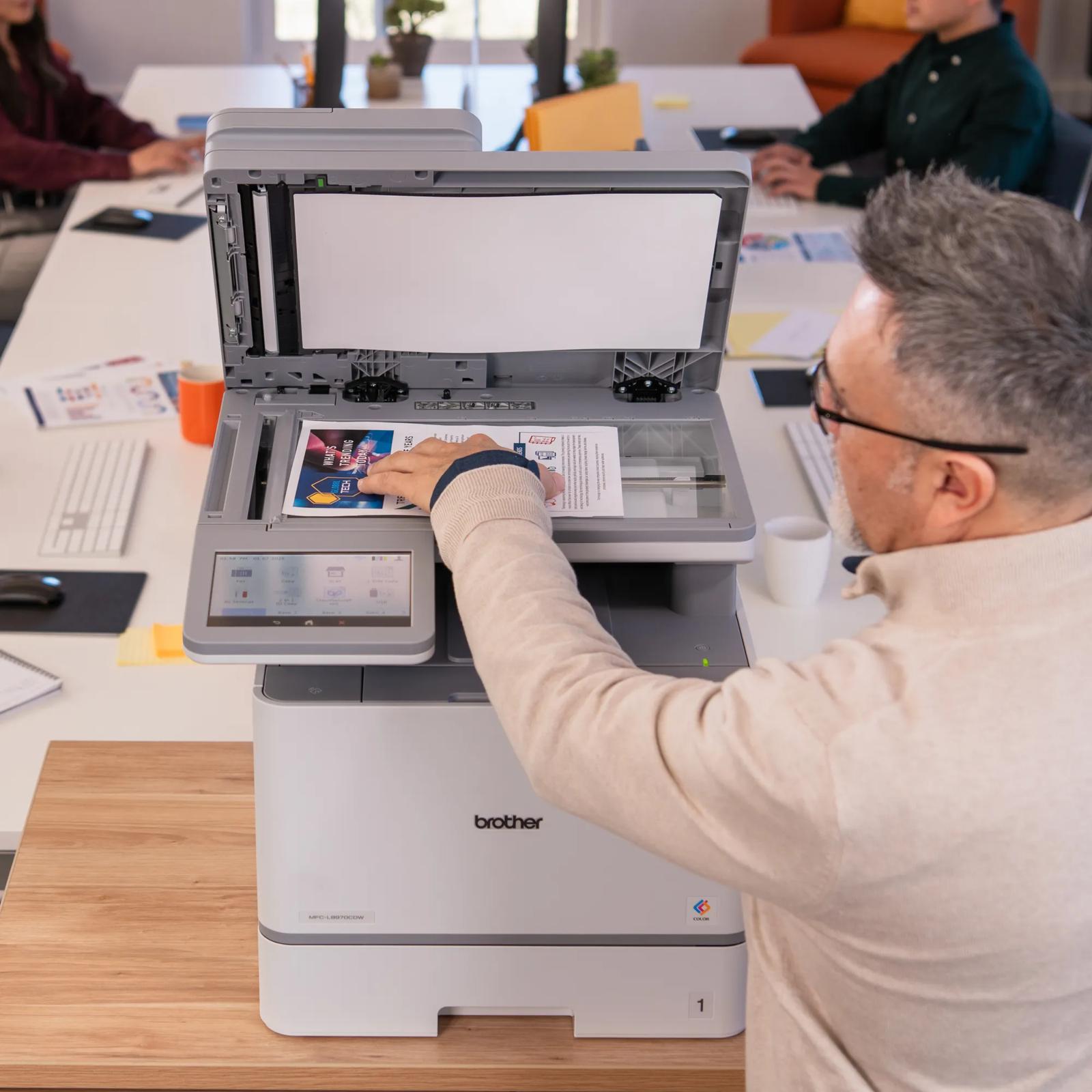 Man scanning documents on Brother MFC-L8970CDW color laser all-in-one printer in office