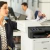 Woman retrieving color document from Brother all-in-one laser printer in office