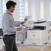 Professional using Brother color laser all-in-one printer with touchscreen in modern office