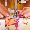Hands guiding floral fabric through Brother sewing machine presser foot during stitching