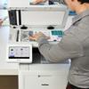Person using Brother all-in-one printer with touchscreen to scan documents in office