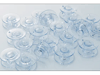 Clear plastic bobbins for Brother sewing machines arranged on white surface
