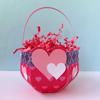 Red and pink heart-decorated basket filled with curled paper shreds and handle