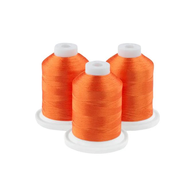 Three spools of dark orange embroidery thread on white bases