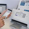 Brother desktop scanner with wireless connectivity and touchscreen, user operating via smartphone