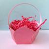 Pink paper basket filled with shredded pink crinkle paper on white surface