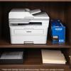 Brother MFC-L2980DW monochrome laser all-in-one printer with toner cartridge on wooden shelf