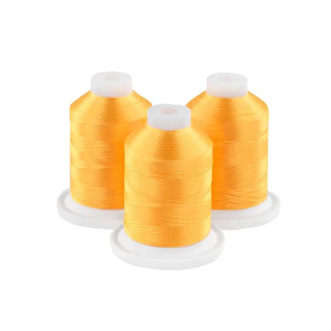 Three spools of bright orange embroidery thread on white bases