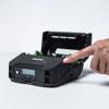 Hand pressing button on Brother portable printer with open paper compartment