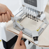 Hands positioning fabric in Brother embroidery machine hoop with multi-needle setup