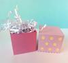 Pink gift boxes with white shredded paper filler on light blue background