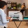 Woman using smartphone with Brother all-in-one inkjet printer in home office