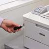 Hand inserting USB drive into Brother HL-L8245CDW color laser printer with touchscreen