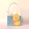 Yellow rubber duck decoration on blue patterned gift bag with clear handle and shredded paper