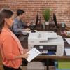 Woman using tablet with Brother all-in-one printer in modern office workspace