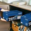 Person storing Brother TN227 toner cartridge 2-pack in office cabinet drawer