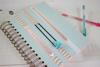 Spiral-bound planner with decorative washi tape and pens on white desk