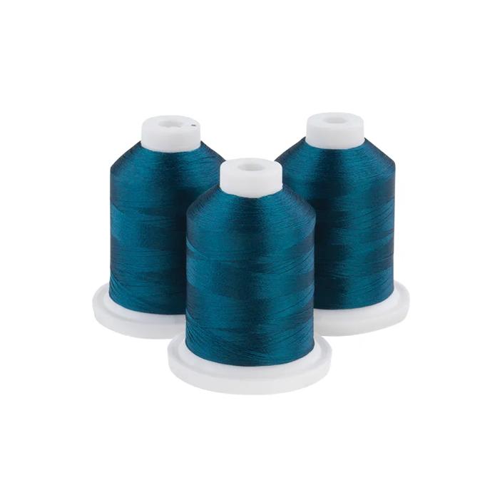 Three dark teal embroidery thread spools on white bases