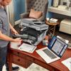 Man replacing toner cartridge in Brother monochrome laser all-in-one printer at home office desk