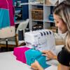 Woman sewing colorful fabric on Brother Air1800 serger in home workspace