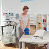 Woman using Brother embroidery machine in home workspace with colorful thread spools