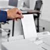 Hand inserting envelope into Brother MFC-J6975DW all-in-one printer in office setting