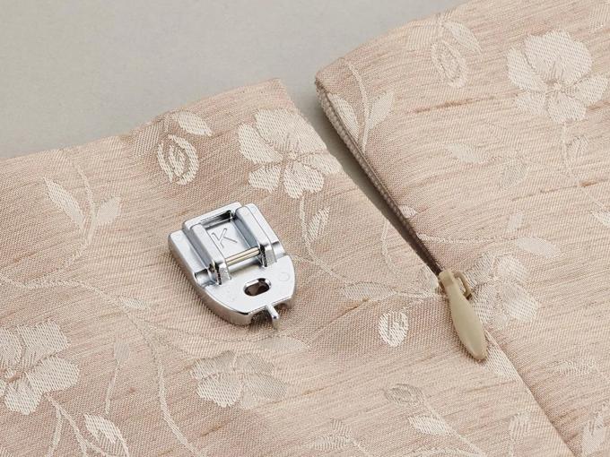 Brother sewing machine presser foot and seam ripper on beige fabric with leaf pattern