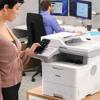 Woman using smartphone to control Brother MFC-EX915DW all-in-one wireless printer in office