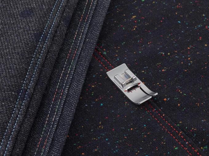 Brother sewing machine presser foot on black fabric with colorful decorative stitching