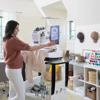 Woman using Brother embroidery machine with touchscreen in bright home studio workspace