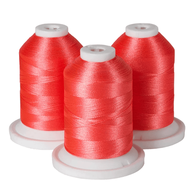 Three spools of red Brother embroidery thread on white bases
