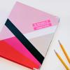 Labeled school notebooks in pink and red with pencils for organizing assignments