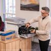 Man replacing toner cartridge in Brother all-in-one laser printer in office setting
