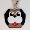 Handmade dog face ornament with black ears, white muzzle, and colorful string hanger