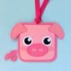 Pink pig-shaped luggage tag with ribbon strap on light blue background